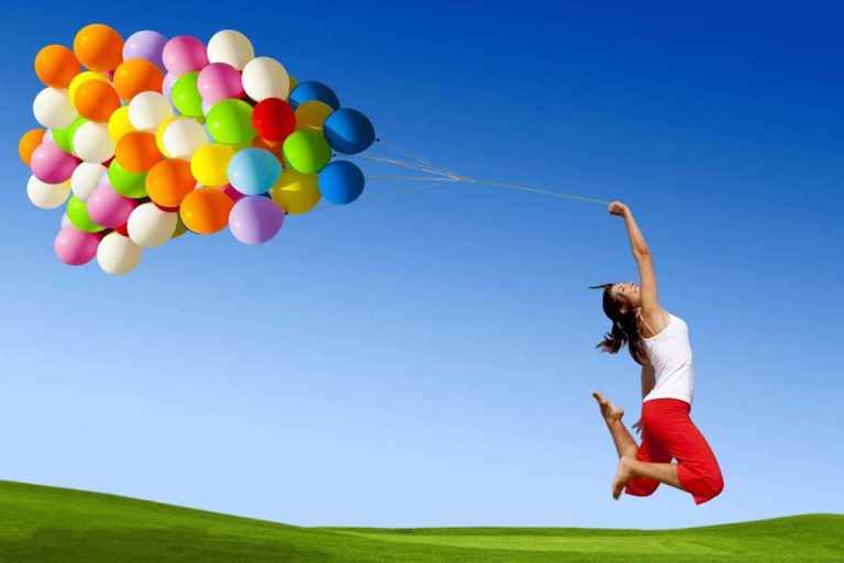woman holding balloons jumping
